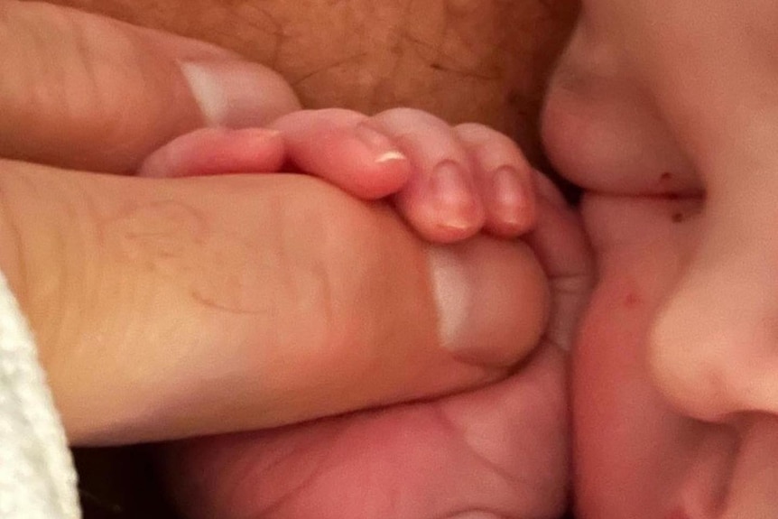 A baby holding a man's finger