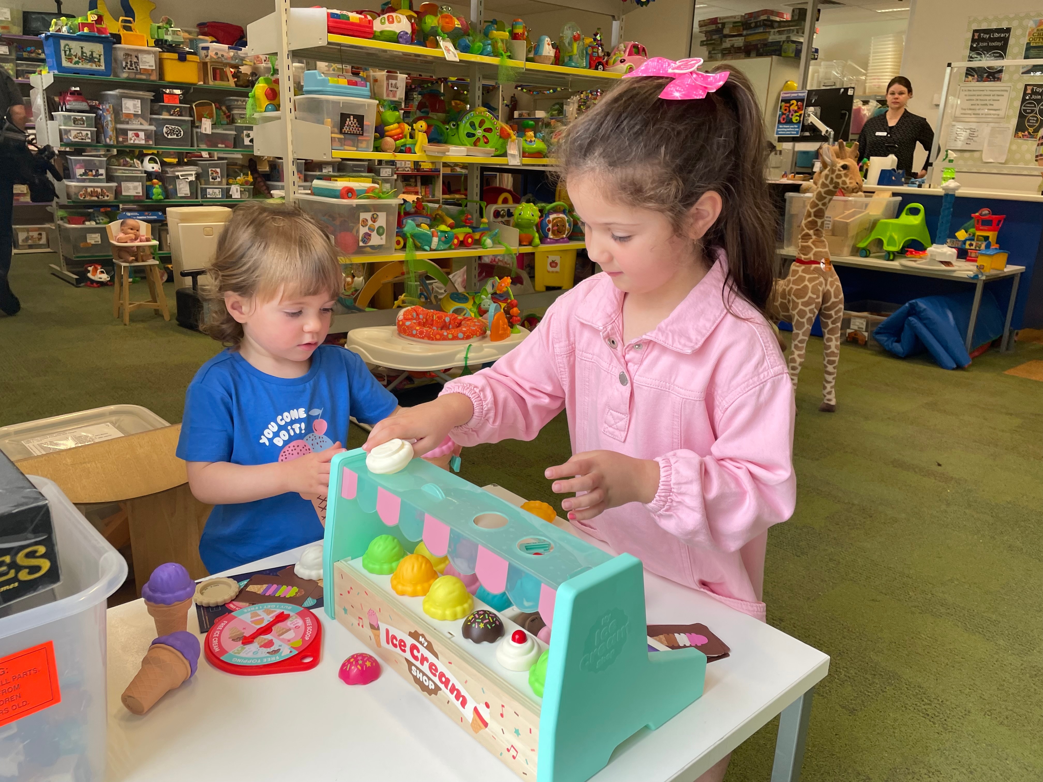 two kids playing with an ice cream cart 