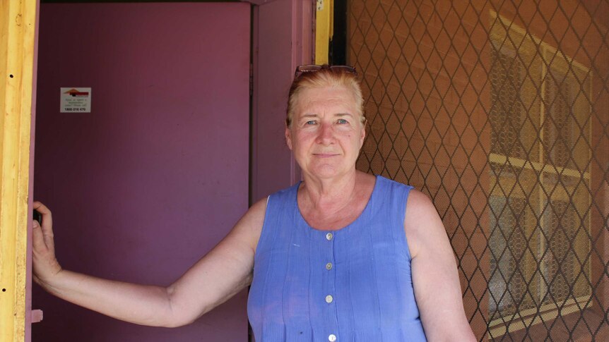 Cheryl North stands by her front door in a blue top.