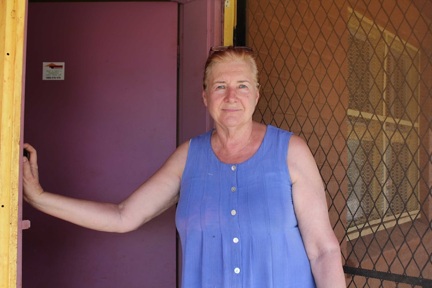 Cheryl North stands by her front door in a blue top.