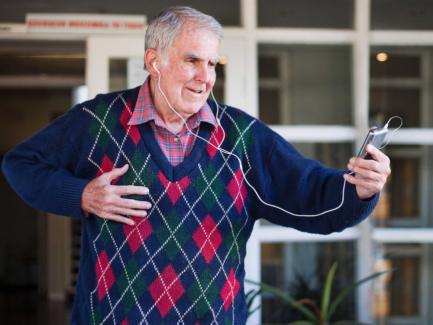 A older man listens to music on a portable device