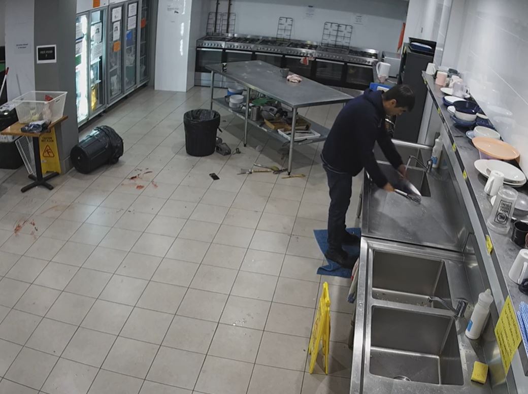 A man stands at a sink washing dishes. 