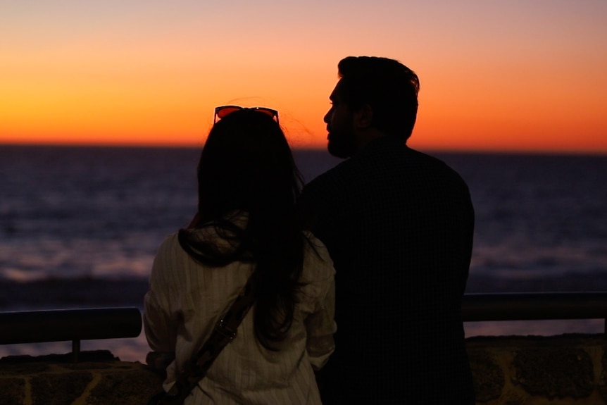A couple embrace while watching a sunset
