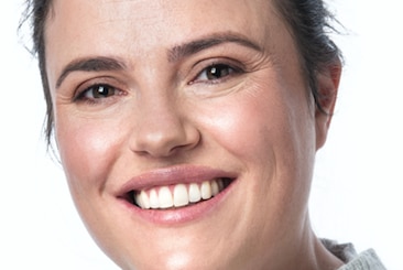 Professional headshot of university researcher smiling, wearing a grey jumper.