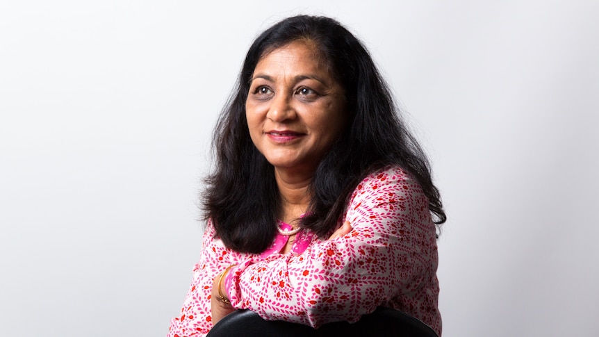 Neeti Pandya sits on a chair.