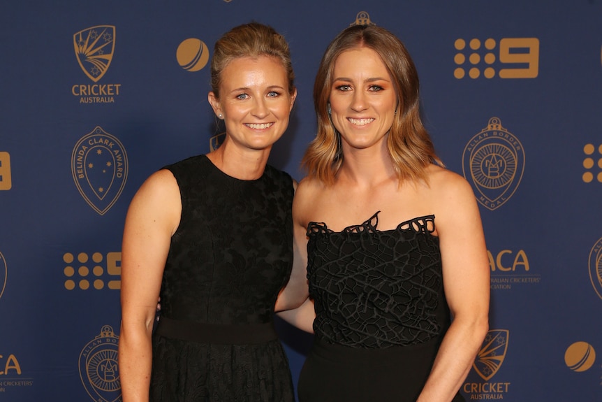 Two women wear black dresses on red carpet.