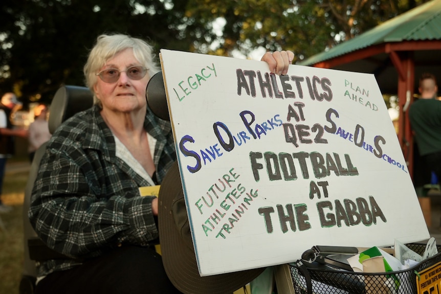 A woman holds a sign that reads 'save our parks, save our school'