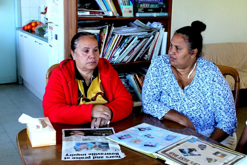 two women sitting a table looking at newspaper clippings