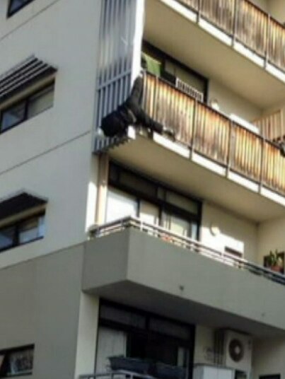 Man dangling from apartment balcony at Kensington Victoria