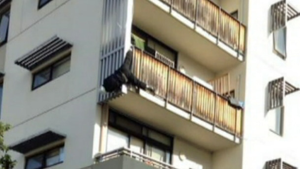 Man dangling from apartment balcony at Kensington Victoria