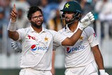 A bespectacled Imam-Ul-Haq has his helmet off and is holding his arms up