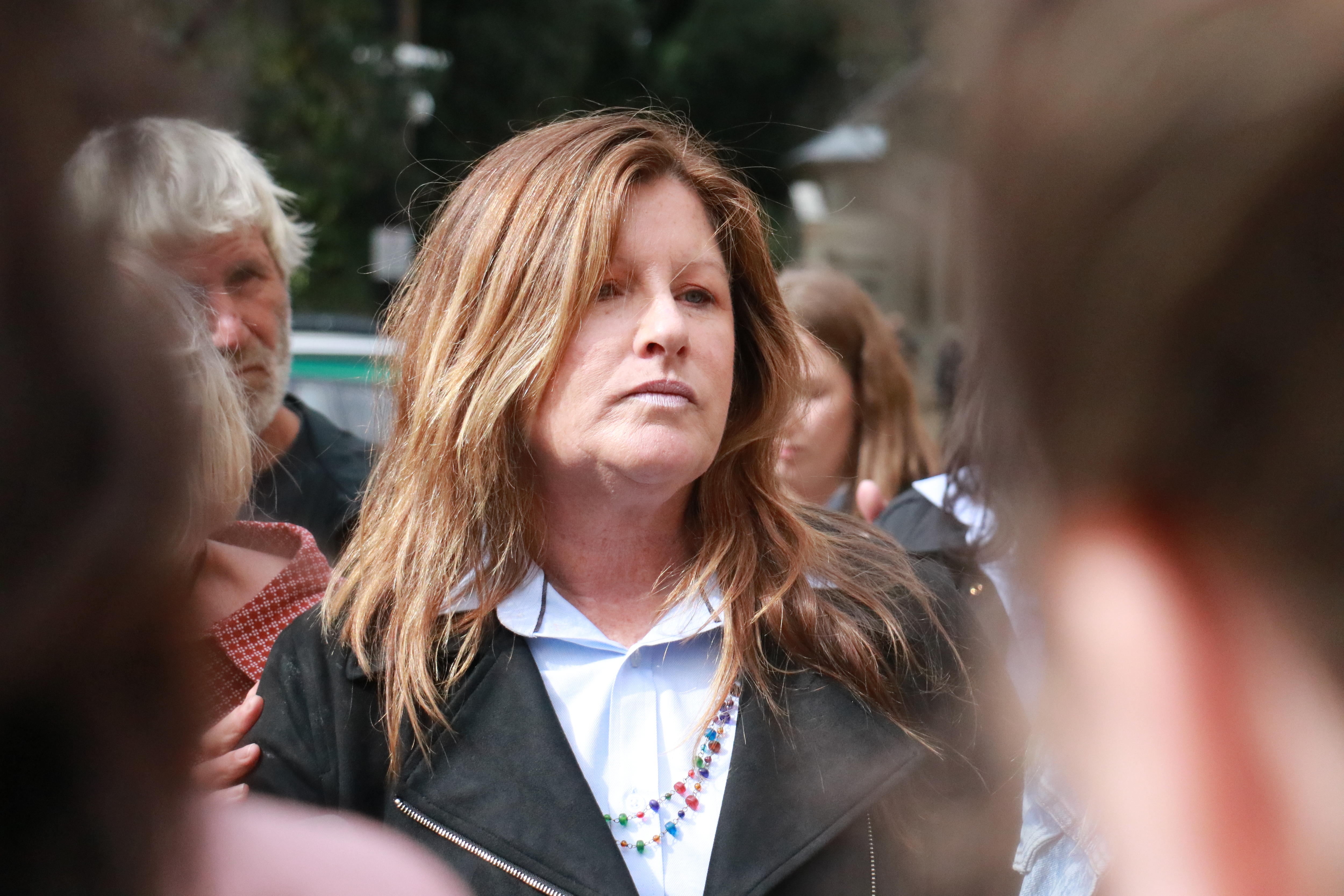 Cheryl wears a somber expression and her long brown hair out