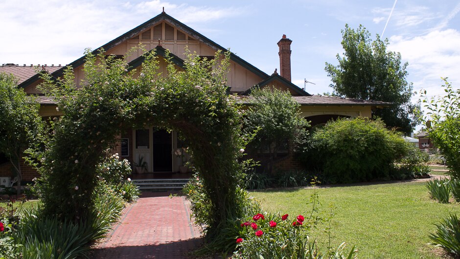 An old federation style home in garden with rose arbour