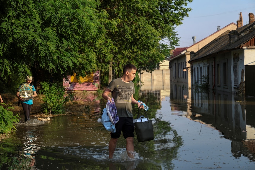 A local resident walks on a flooded street after the Nova Kakhovka dam breached,