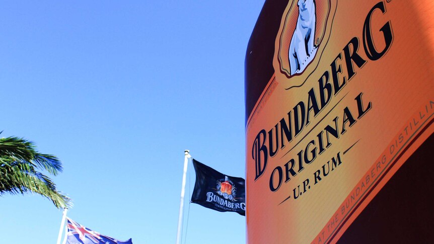 Flags fly behind a huge replica Bundaberg Rum bottle outside the Bundaberg Rum distillery in Bundaberg East.