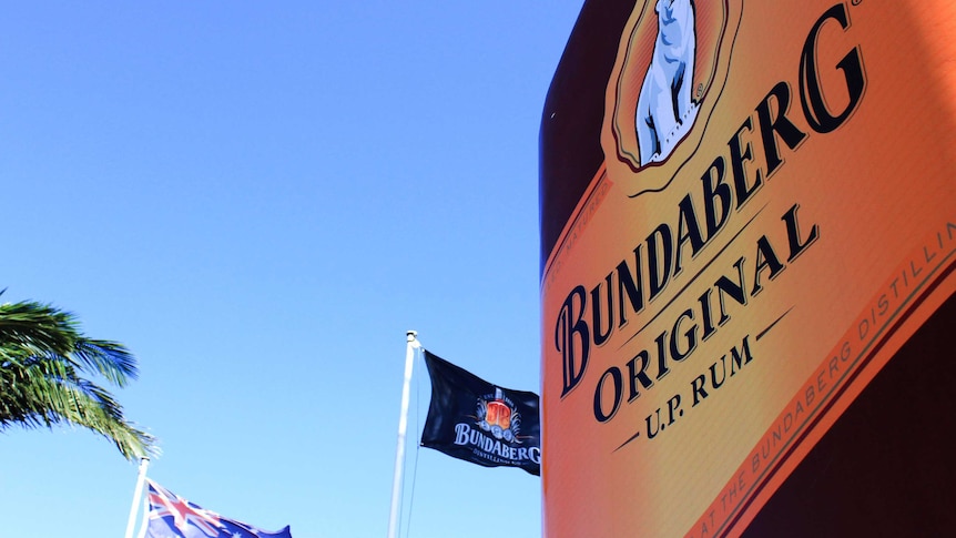 Flags fly behind a huge replica Bundaberg Rum bottle outside the Bundaberg Rum distillery in Bundaberg East.