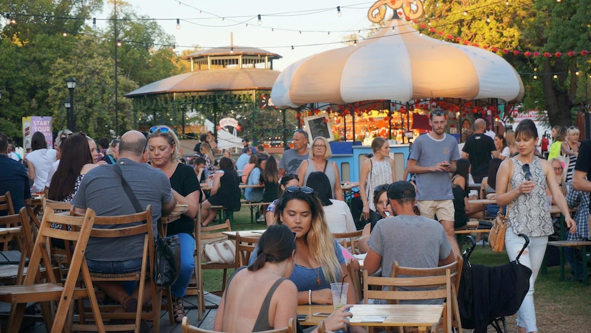 People sit at tables and alk along paths at the Pleasure Gardens, a Fringe venue in Perth.
