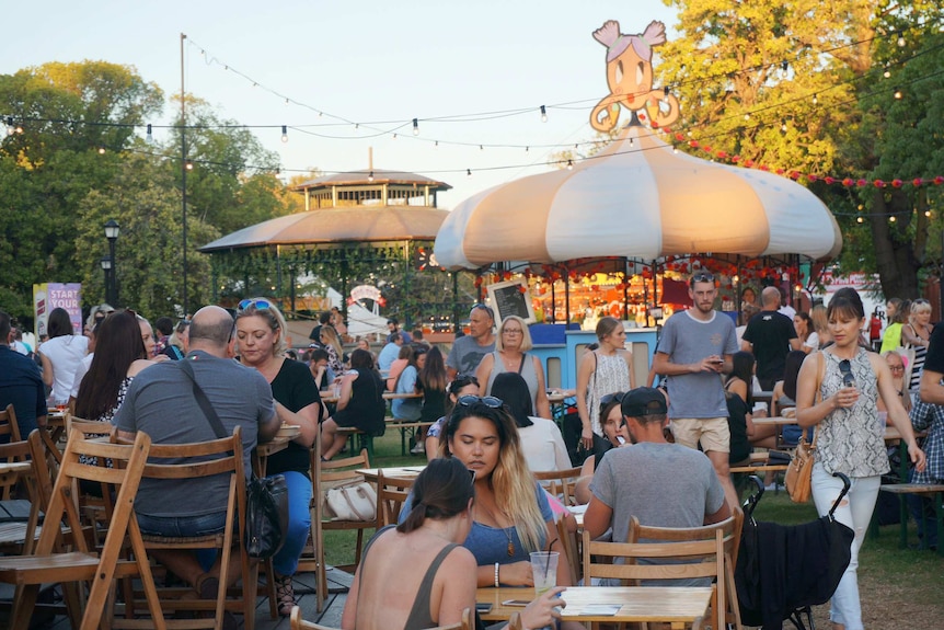 People sit at tables and alk along paths at the Pleasure Gardens, a Fringe venue in Perth.