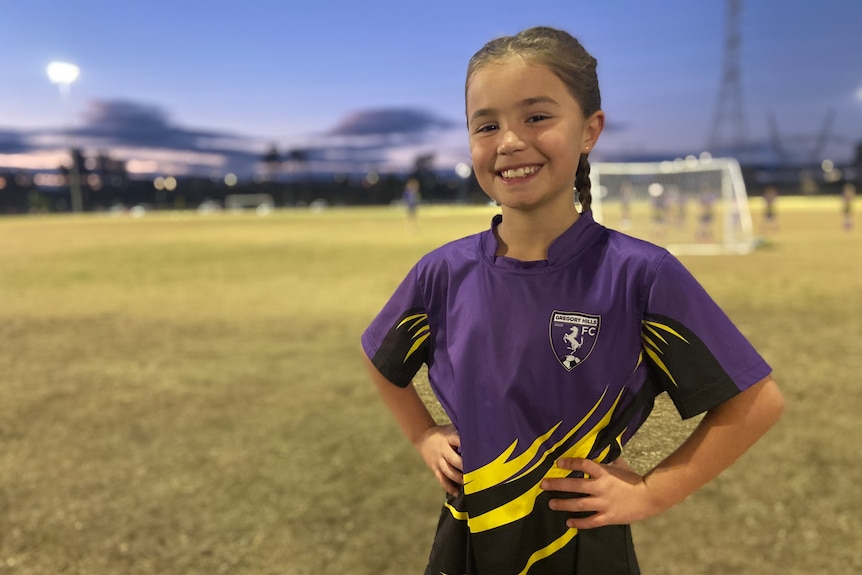 Young girl in purple soccer uniform on a soccer field.
