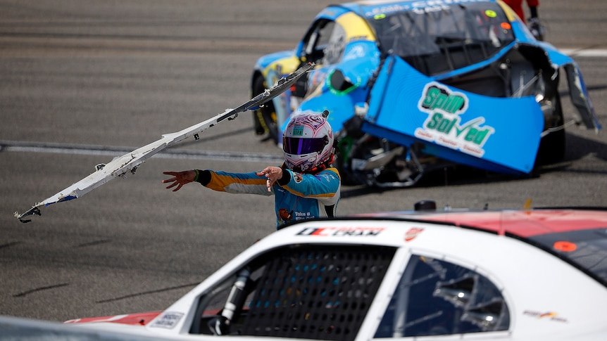 NASCAR driving Joey Gase throws his bumper at a car driving past.