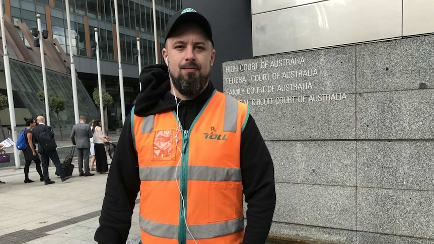 Neil Erikson wears an orange Toll Holdings vest outside the Federal Court.