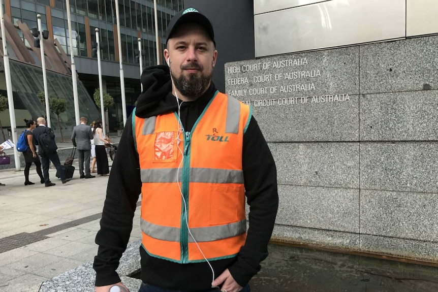 Neil Erikson wears an orange Toll Holdings vest outside the Federal Court.