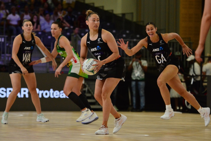 A netball player wearing black looks to pass the ball during a match