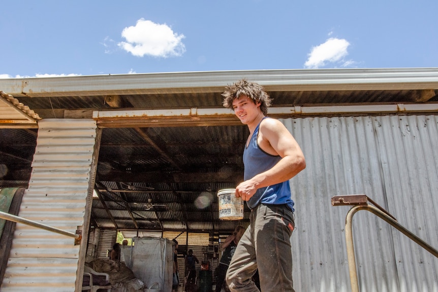 A sheep shearer in front of the shearing shed