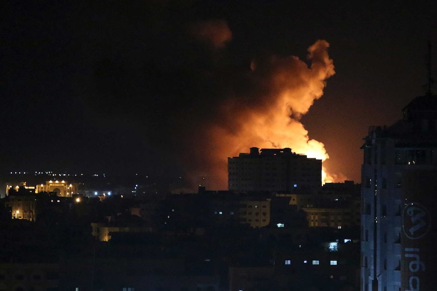 Smoke rises from a building in Gaza at night.
