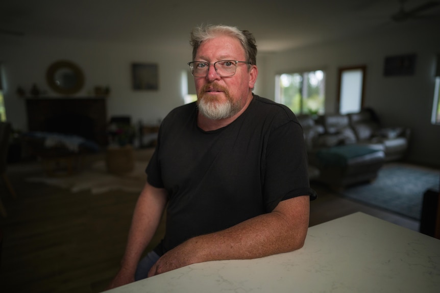 Man wearing a black shirt and glasses sitting at a table.