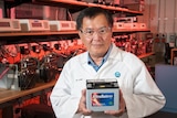 CSIRO scientist Dr Lam Lan in white coat standing up and holding an Ultrabattery