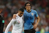 Ronaldo helps Cavani off the field as the referee watches on.