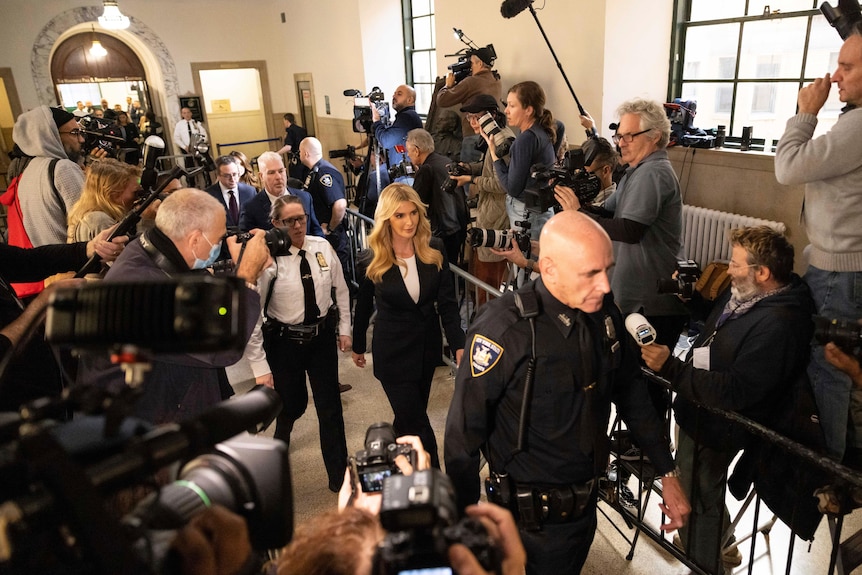 Ivanka Trump è circondata dalla sicurezza mentre passa davanti a una folla di fotografi su entrambi i lati del tribunale.