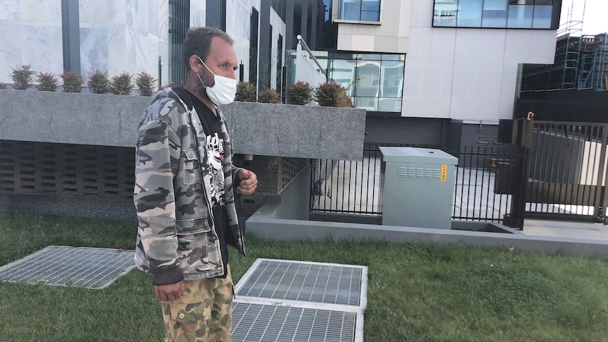 A man wearing camoflague walks outside a building