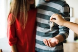 A young couple is handed a set of silver house keys.