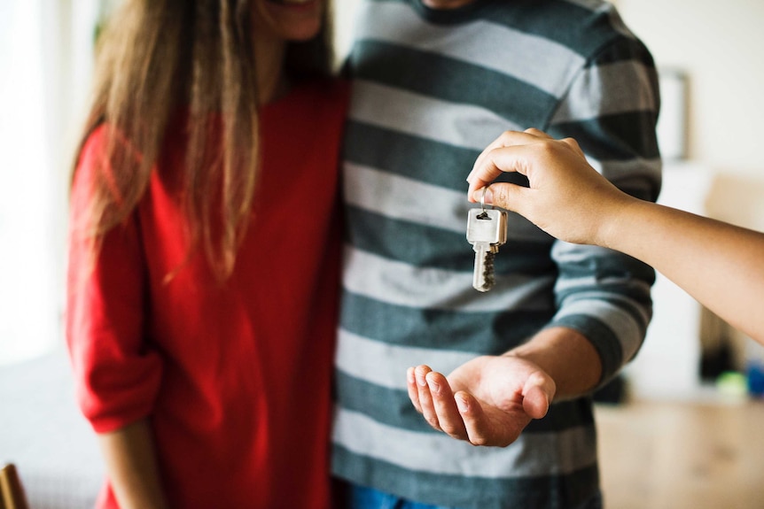 A young couple is handed a set of silver house keys.