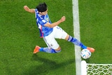 Kaoru Mitoma stretches to get his foot to the ball, which is right on the back edge of the goal line