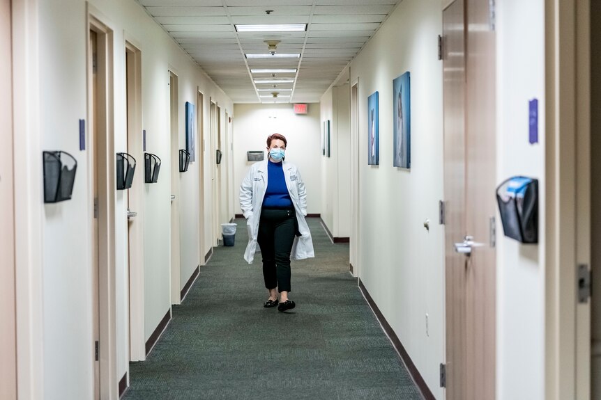A doctor walks down a hallway.