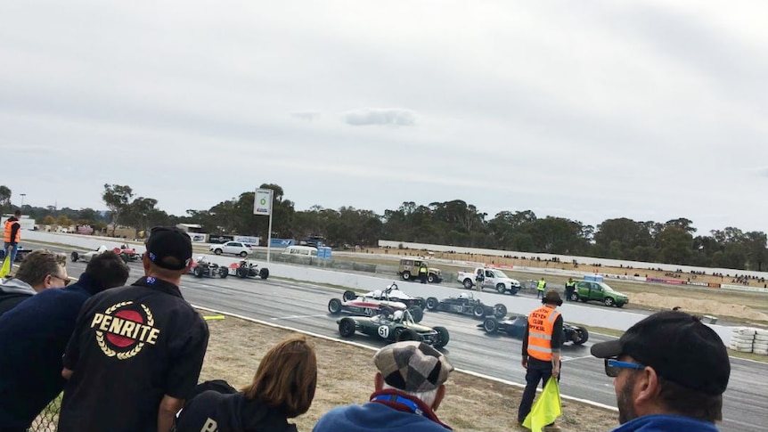 Spectators watch racing cars on track.
