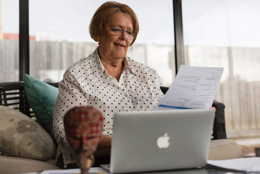 Denyse McKay looks at a document in front of a laptop.