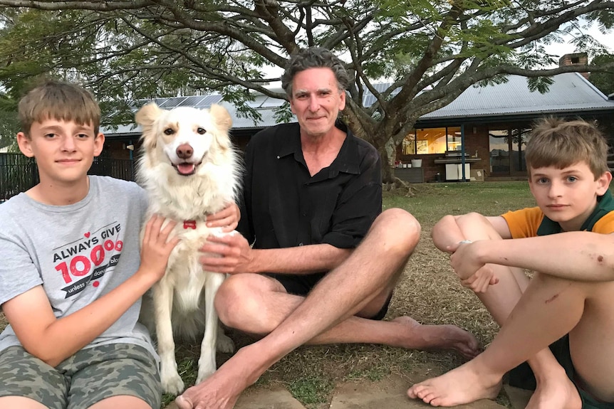 Dave Bellingham sits outside with his two sons and dog