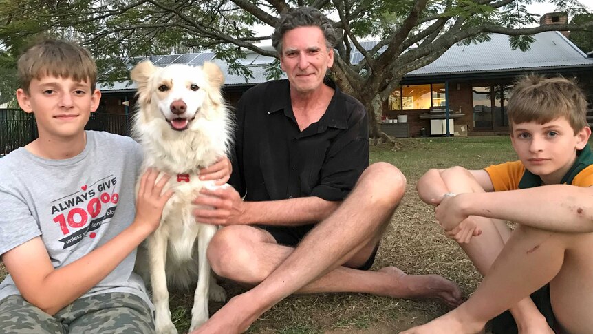 Dave Bellingham sits outside with his two sons and dog