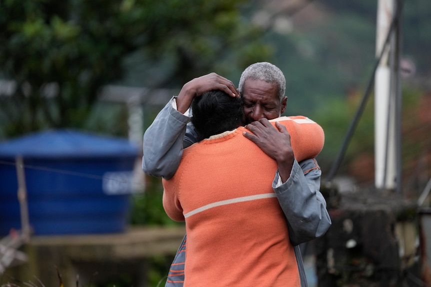 Residents embrace as they wait for a report for missing relatives in an area affected by landslides.