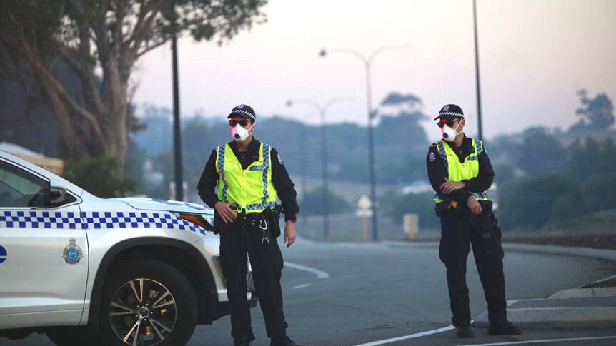 Police wear face masks as they control a roadblock in Yanchep