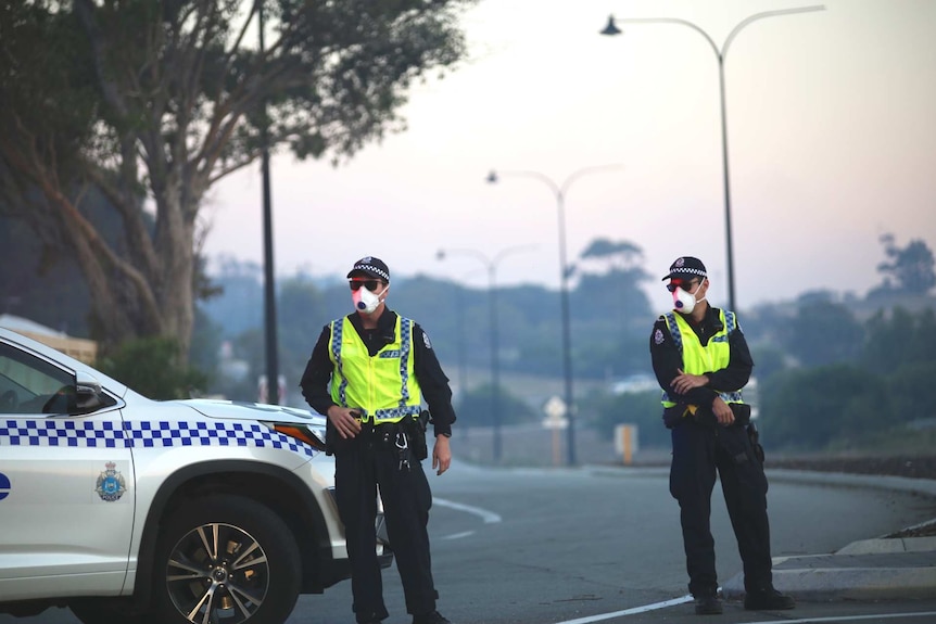 Police wear face masks as they control a roadblock in Yanchep