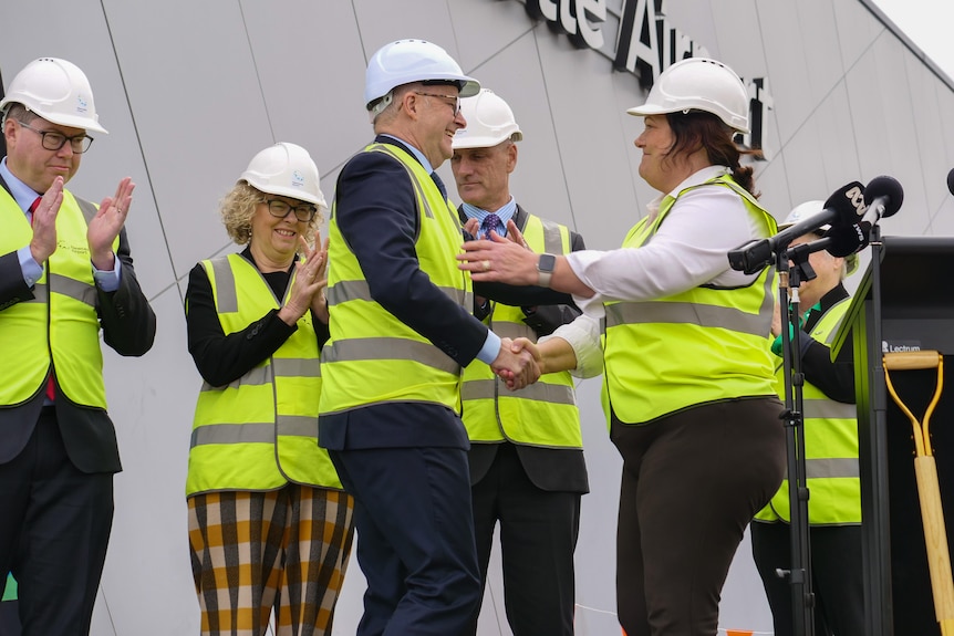 The prime minister is wearing hi vis, and he's shaking the hand of Meryl Swanson at a construction site at Newcastle airport