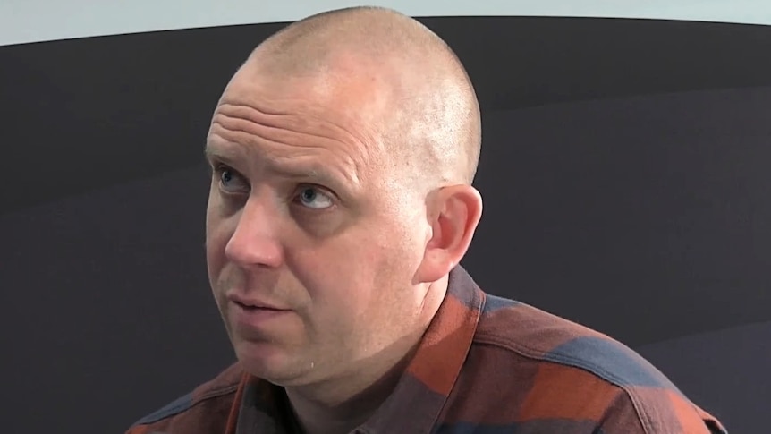 A bald man in a checkered shirt.