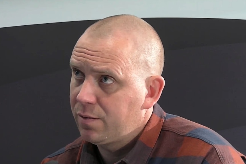 A bald man in a checkered shirt.