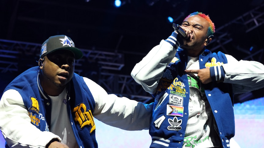 Two members of Brockhampton performing at Coachella, wearing blue and white jerseys