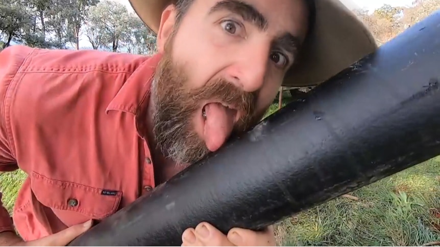 Photo of Tim Thompson licking a fence post